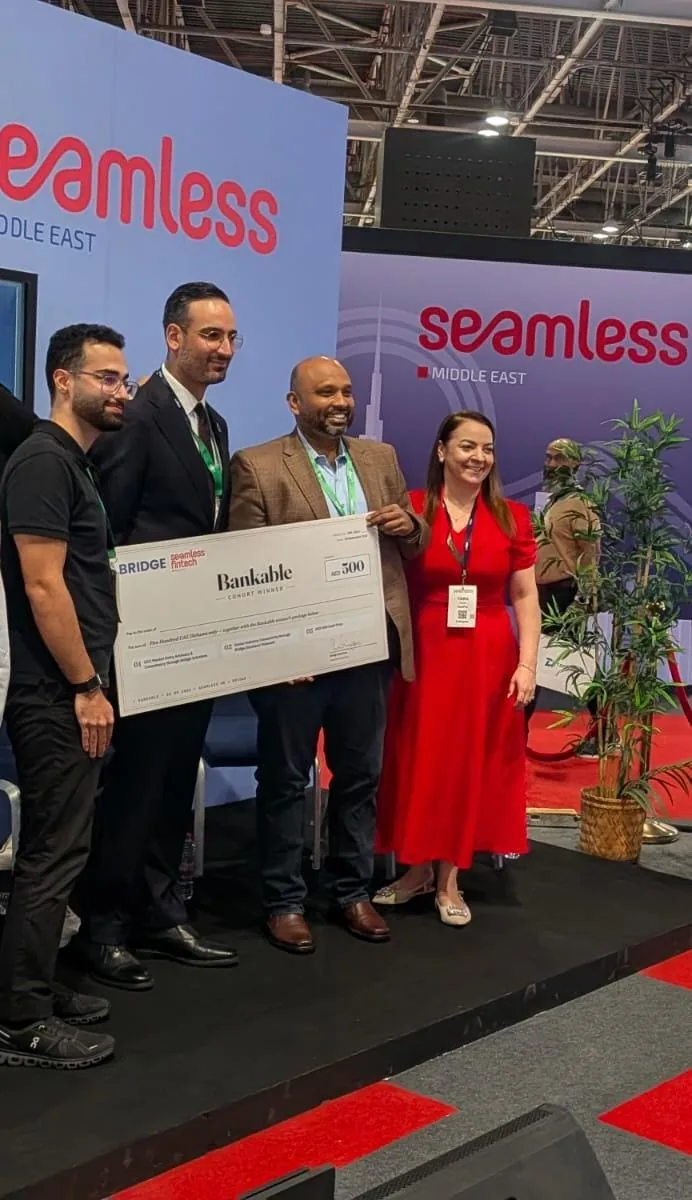 Sridhar Kotari with a group on stage holding a BANKABLE Cohort Winner presentation cheque beneath Seamless Middle East signage